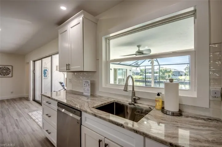 The kitchen features white cabinetry, a stainless steel sink, and light-colored countertops