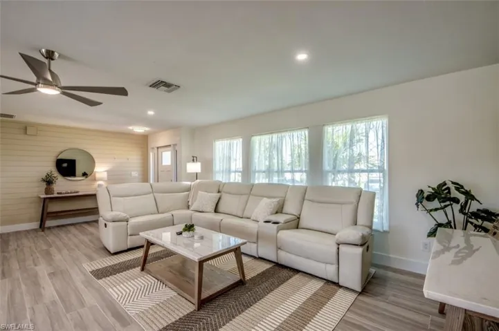 The open-concept living space features light wood-look flooring, recessed lighting, and a ceiling fan
