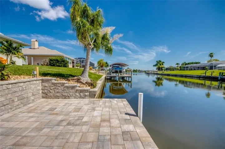 The property features a paver patio with a stone retaining wall, offering direct access to the canal