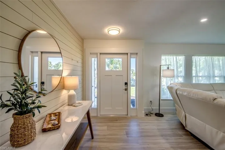 The entryway features a front door with glass panes, sidelight windows, and light wood plank wall detailing