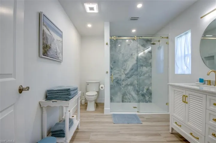 The bathroom features a spacious walk-in shower with a glass enclosure and a vanity with a white countertop and gold-toned fixtures
