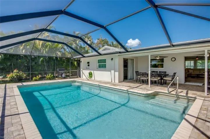 The property features an outdoor swimming pool, screened enclosure, and a paved patio area