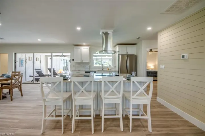 The kitchen features white cabinetry, stainless steel appliances, and a central island with countertop seating