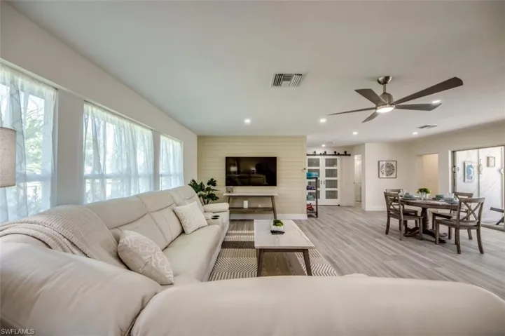 Spacious living area featuring light-colored flooring, recessed lighting, and a ceiling fan