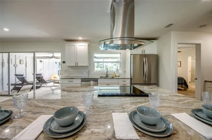 The kitchen features a spacious island with a cooktop and a modern stainless steel range hood