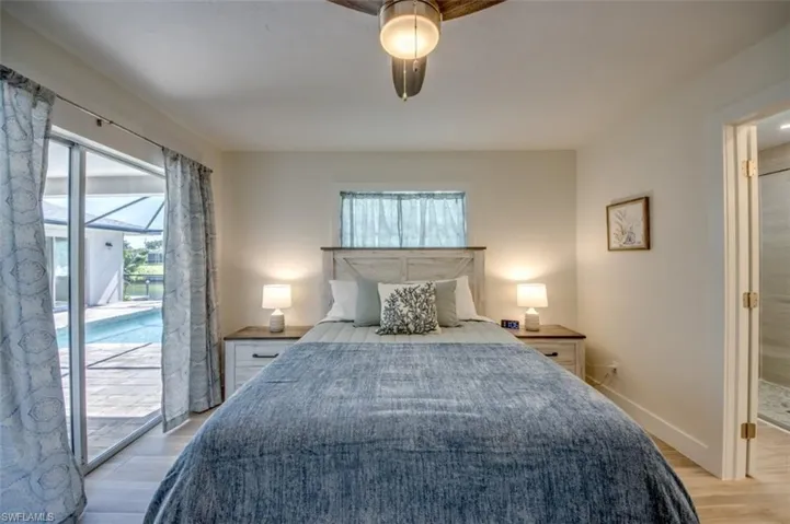 Bedroom featuring a ceiling fan with light, light-colored walls, and a sliding glass door leading to a screened-in pool area