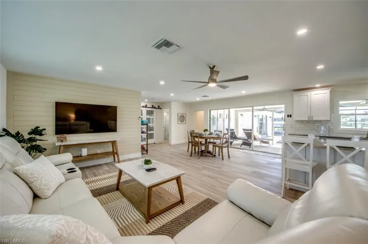 This spacious living area features light-toned flooring, recessed lighting, and a ceiling fan