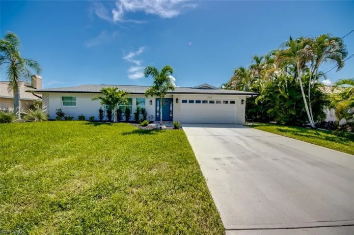 This property features a single-story home with a white exterior, a blue front door, and a two-car garage