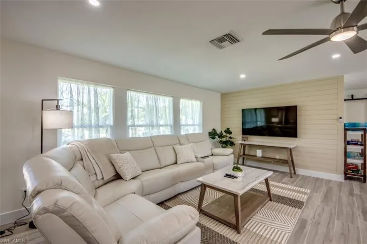 The living area features light-colored walls, recessed lighting, and a ceiling fan