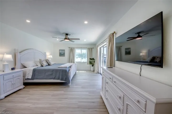 This spacious room features light-toned flooring, recessed lighting, and a ceiling fan