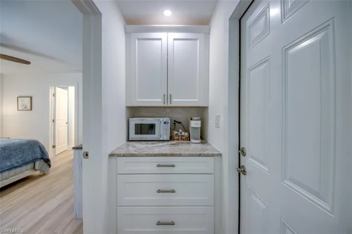 Compact kitchenette featuring white cabinetry, a stone countertop, and a tiled backsplash