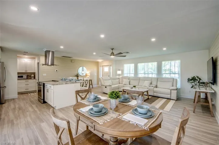 Open concept living area featuring wood-look tile flooring, white shaker cabinetry, stainless steel kitchen appliances, and recessed lighting