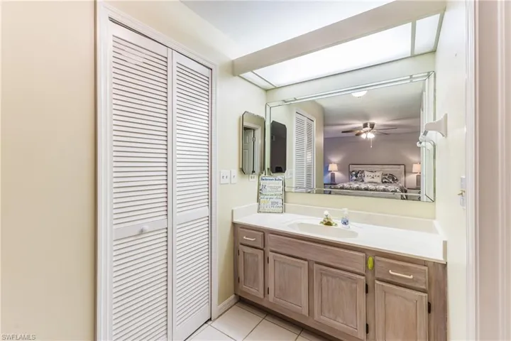 Bathroom featuring a closet, ensuite bath, vanity, light tile patterned floors, and ceiling fan