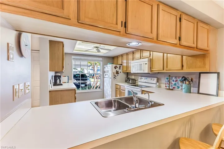 Kitchen featuring light countertops, white appliances, a kitchen breakfast bar, and ceiling fan