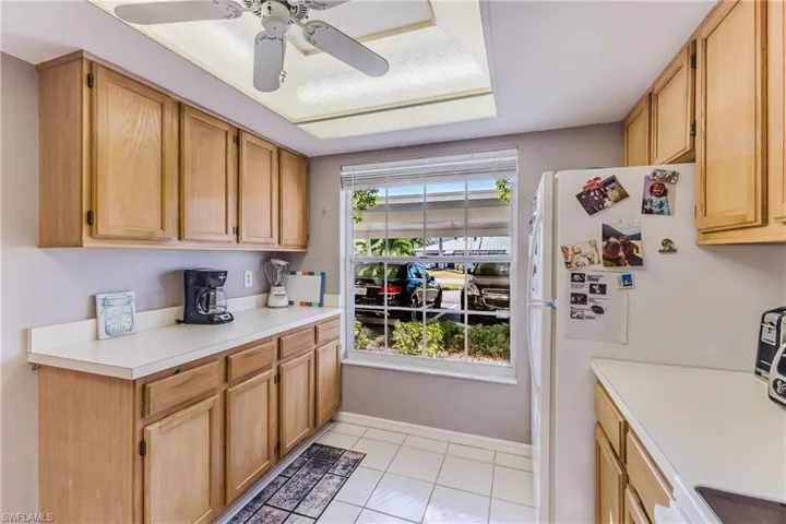 Kitchen featuring white appliances, light countertops, light tile patterned flooring, and ceiling fan