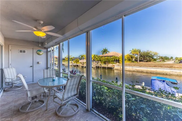 Sunroom featuring a ceiling fan, a water view, and tile patterned flooring