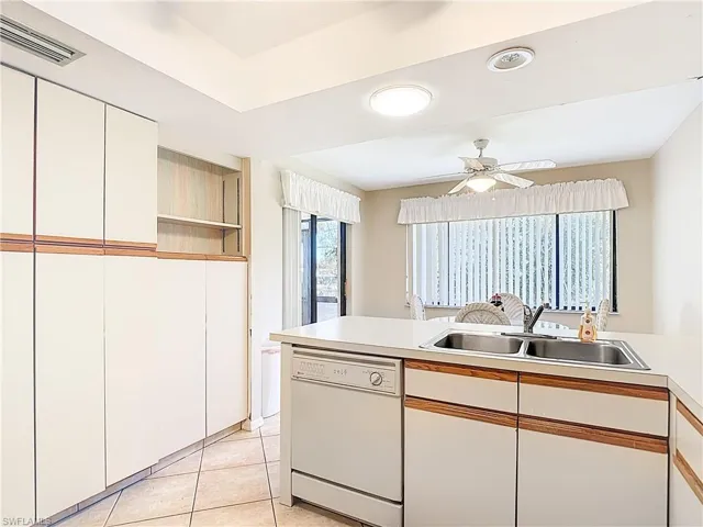 Kitchen with dual tone cabinets, light countertops, dishwasher, light tile patterned floors, and ceiling fan