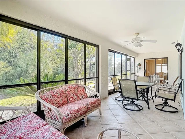 Sunroom / solarium with a textured wall, a ceiling fan, tile patterned flooring, and outdoor dining space