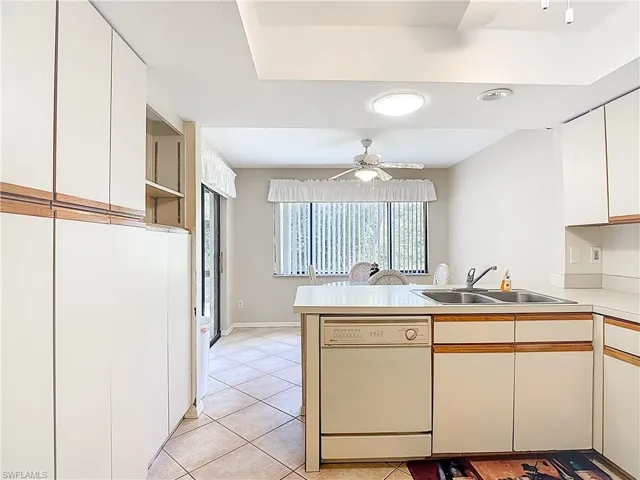 Kitchen with two tone cabinetry, white dishwasher, light countertops, ceiling fan, and light tile patterned flooring