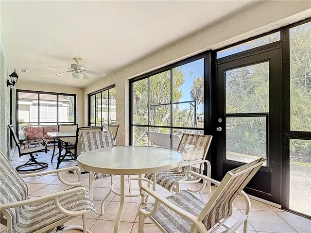 Sunroom featuring outdoor dining space, a ceiling fan, tile patterned floors, and a textured wall