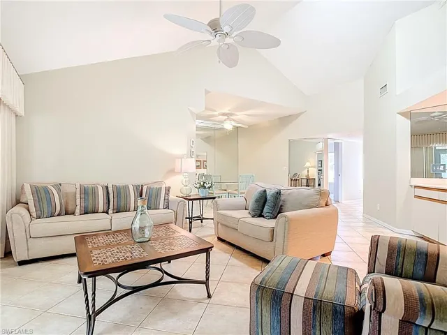 Living area featuring ceiling fan, light tile patterned floors, and lofted ceiling