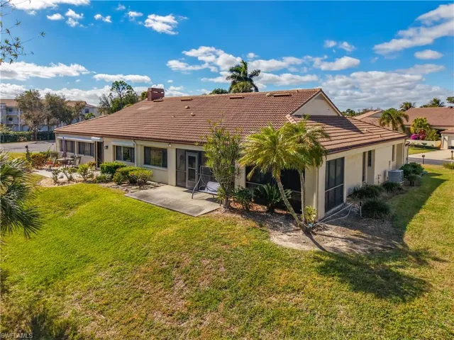 Back of property with a tiled roof, a sunroom, stucco siding, and a yard