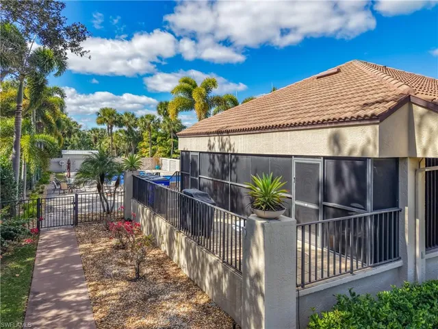 View of side of property featuring stucco siding, a gate, a tile roof, and a sunroom