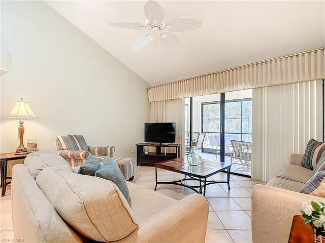 Living room featuring vaulted ceiling, a ceiling fan, and light tile patterned floors