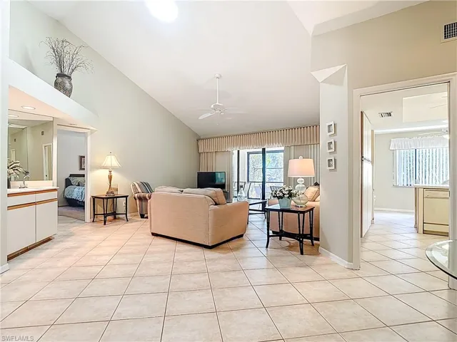 Living room featuring vaulted ceiling, light tile patterned floors, and ceiling fan