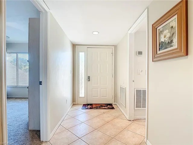 Foyer with light colored carpet, light tile patterned flooring, and recessed lighting