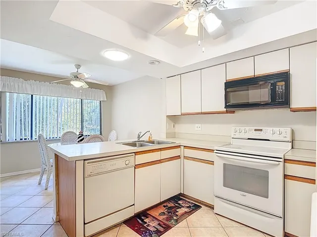Kitchen featuring white appliances, ceiling fan, light countertops, and two tone cabinets