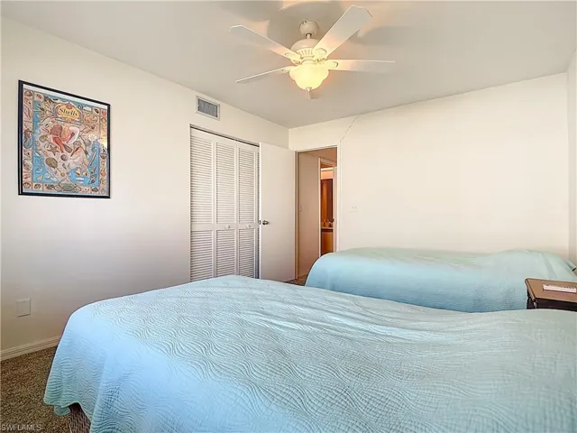 Carpeted bedroom with a ceiling fan and a closet