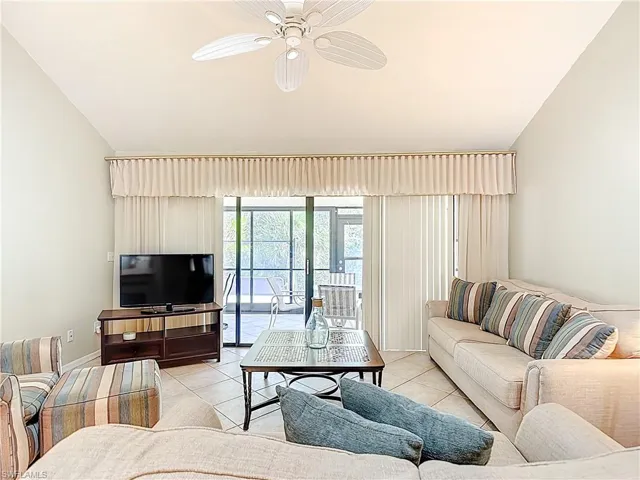 Living area featuring a ceiling fan, vaulted ceiling, and tile patterned floors