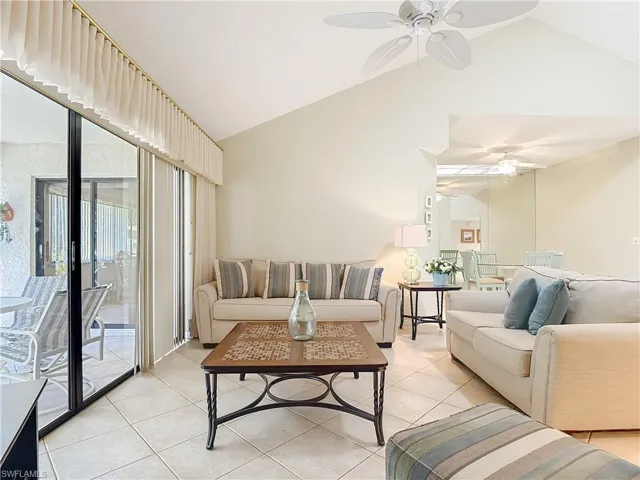Living area featuring lofted ceiling, light tile patterned flooring, and a ceiling fan