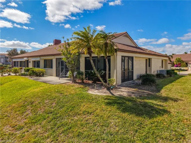 Back of property with stucco siding, a sunroom, a yard, a tile roof, and a patio area