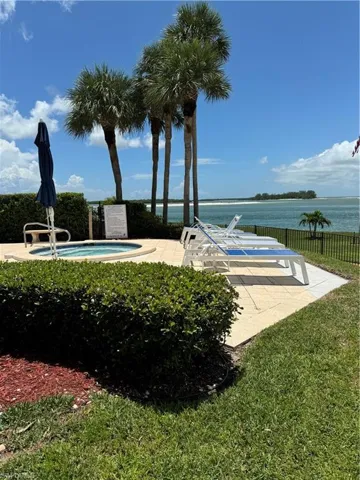 View of home's community featuring a jacuzzi, a water view, and a lawn
