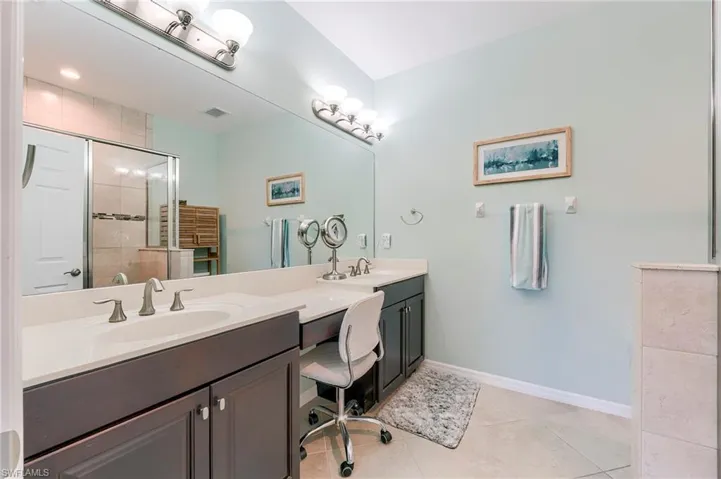 Bathroom featuring a shower stall, double vanity, and light tile patterned floors