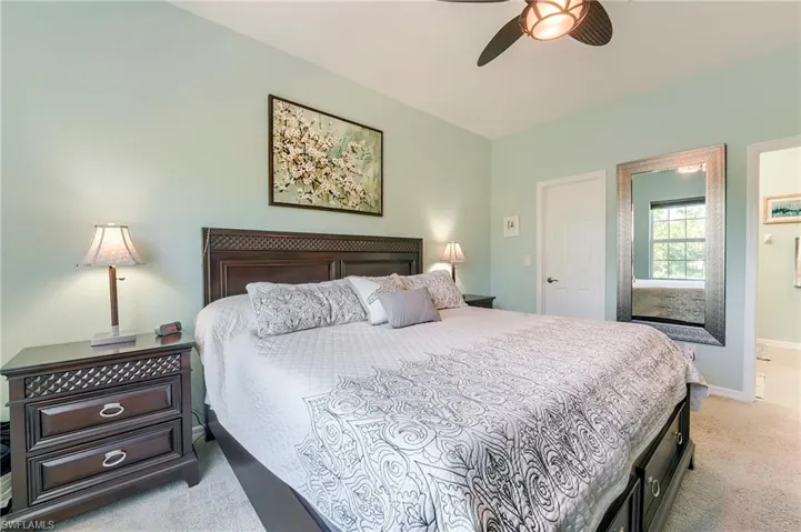 Bedroom with light carpet, a ceiling fan, and ensuite bathroom