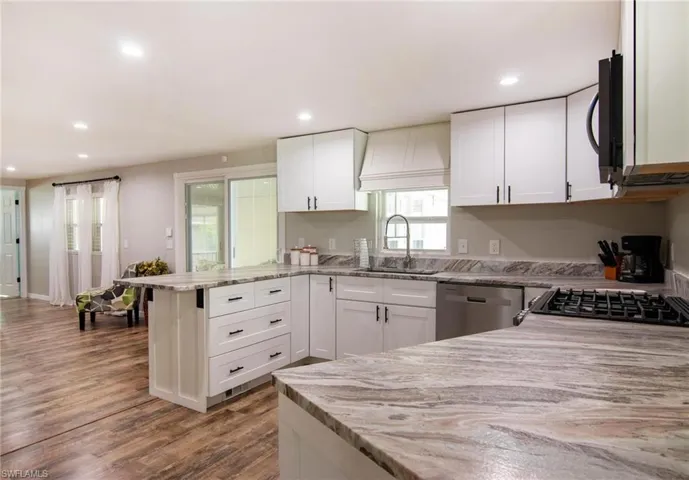 Kitchen with white cabinetry, sink, kitchen peninsula, and dishwasher
