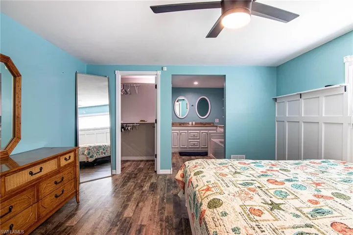 Bedroom featuring connected bathroom, a walk in closet, dark hardwood / wood-style flooring, a closet, and ceiling fan