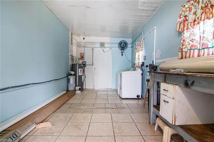 Washroom with washer / dryer, water heater, and light tile patterned floors