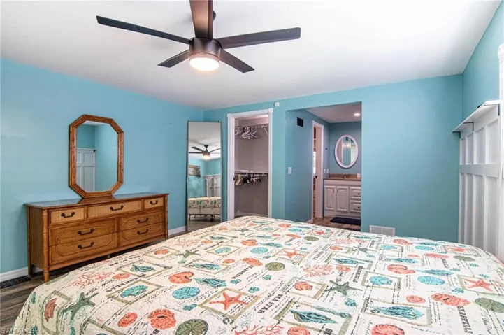 Bedroom with dark hardwood / wood-style floors, connected bathroom, a walk in closet, ceiling fan, and a closet