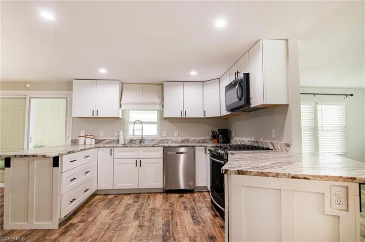 Kitchen featuring sink, dishwasher, range with gas stovetop, white cabinets, and kitchen peninsula