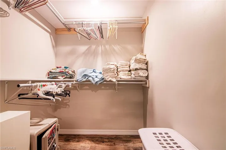 Spacious closet with dark hardwood / wood-style floors