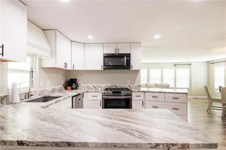 Kitchen with white cabinetry, sink, stainless steel appliances, and kitchen peninsula