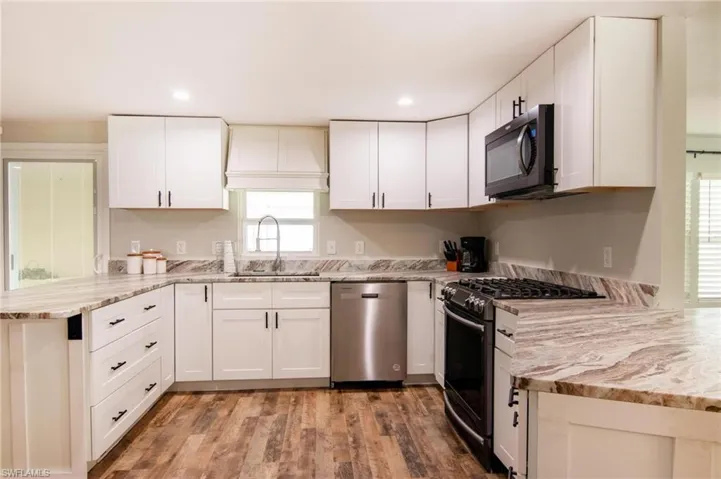 Kitchen with sink, range with gas cooktop, white cabinets, and dishwasher