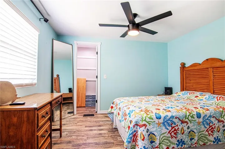 Bedroom with ceiling fan, a spacious closet, and light hardwood / wood-style flooring