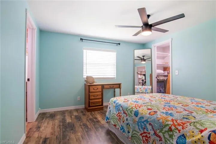 Bedroom featuring a walk in closet, dark hardwood / wood-style floors, ceiling fan, and a closet