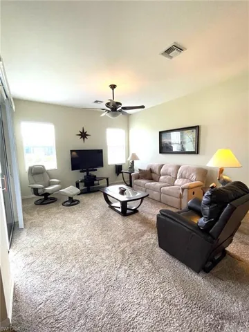 Living room with a wealth of natural light, ceiling fan, and carpet