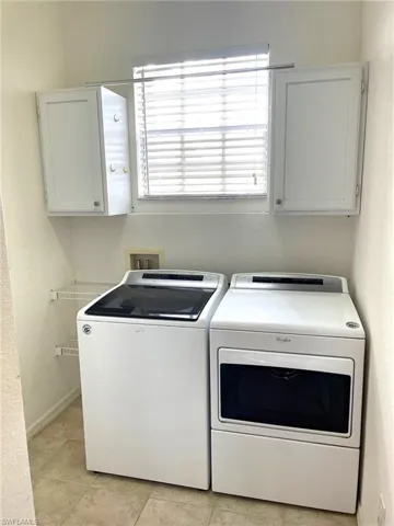 Clothes washing area featuring cabinets, separate washer and dryer